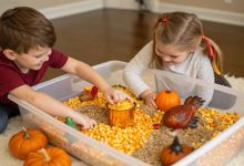 Kids playing with a Thanksgiving sensory bin filled with corn kernels mini pumpkins and turkey toys